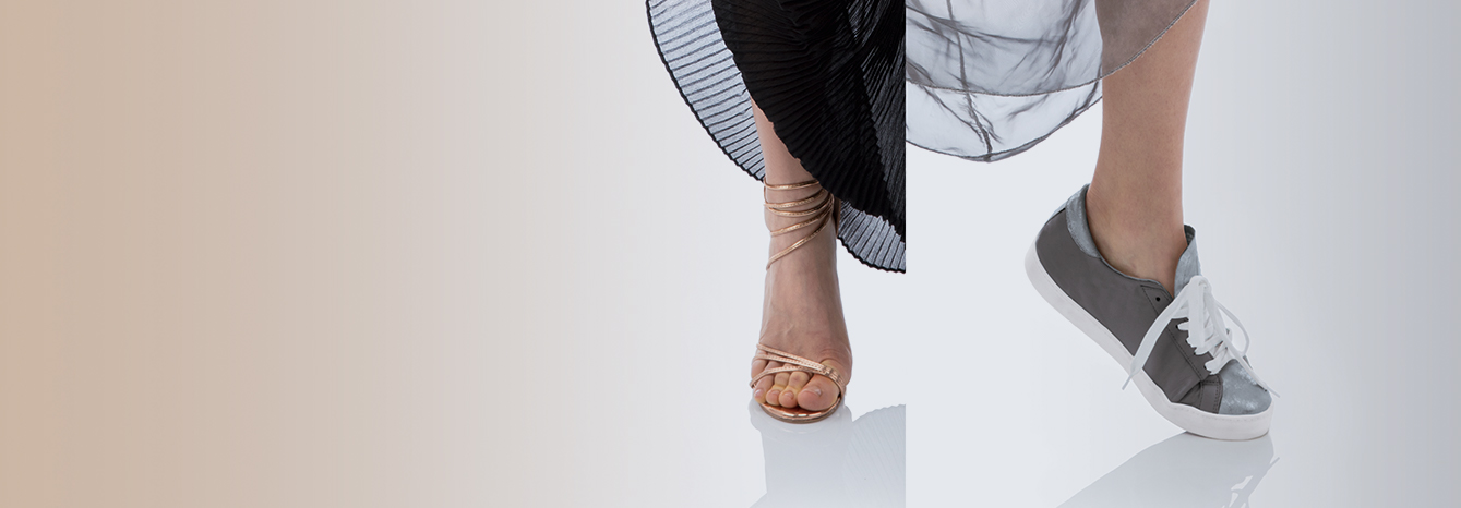 A sandal and a grey sneaker side by side under pleated skirts